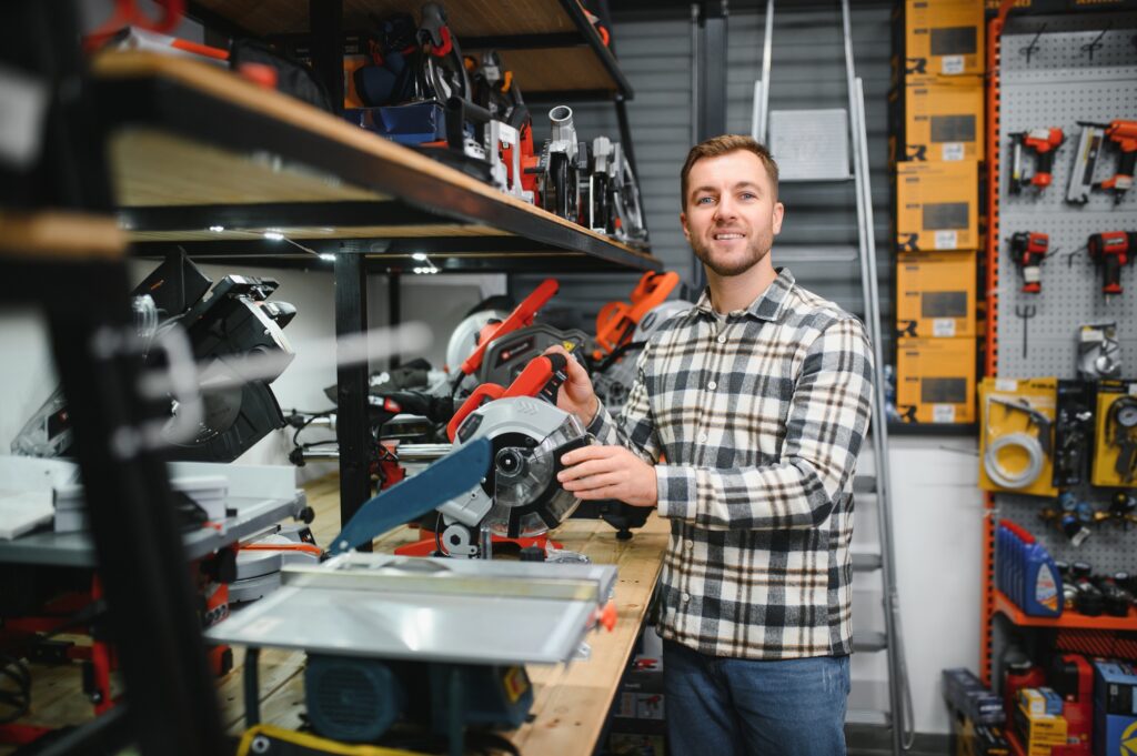 Confident smiling salesman on foreground in power tools store.